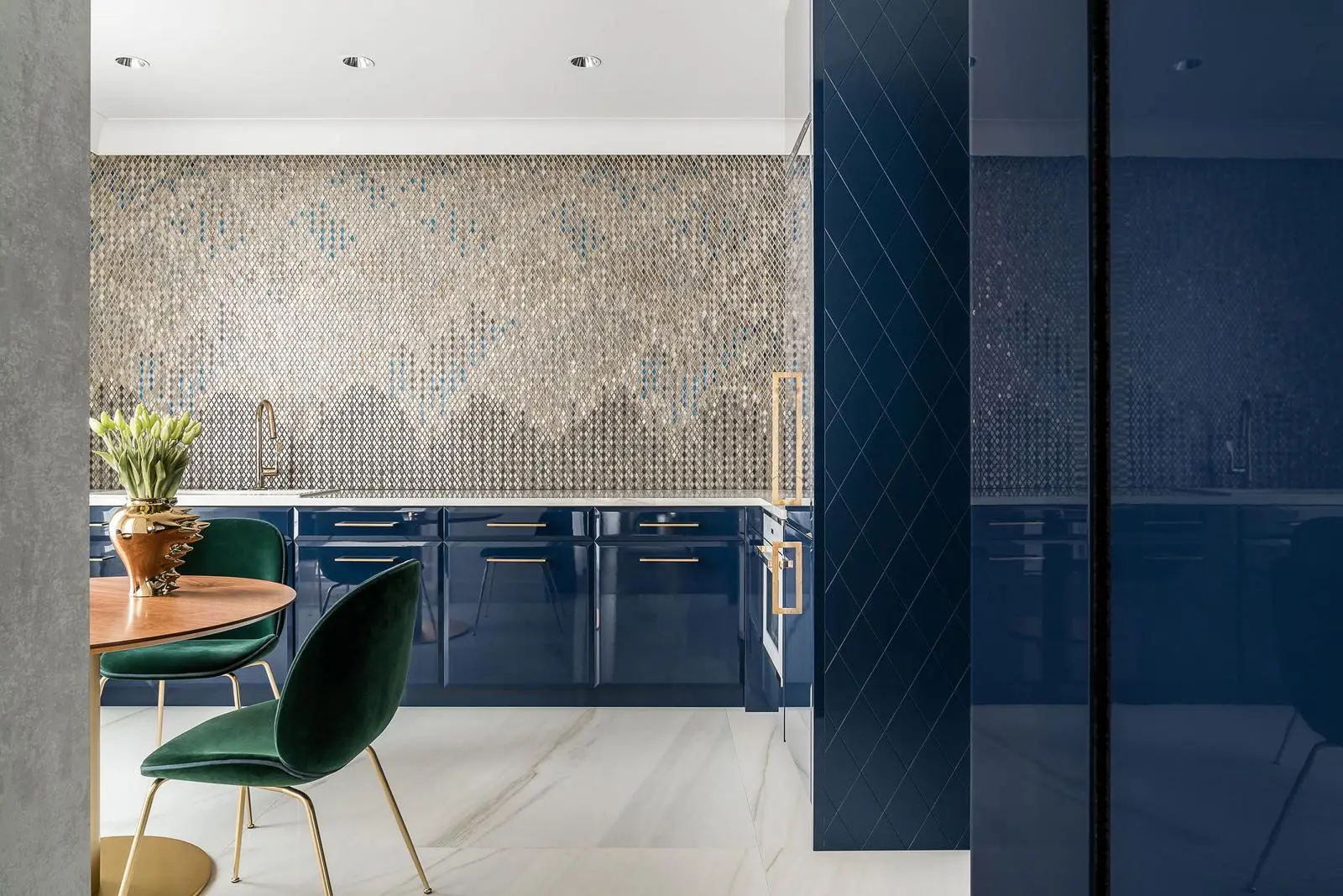 Nowoczesna kuchnia z granatowymi szafkami, zielonymi aksamitnymi krzesłami i metaliczną mozaiką na backsplashu w Gdańsku
