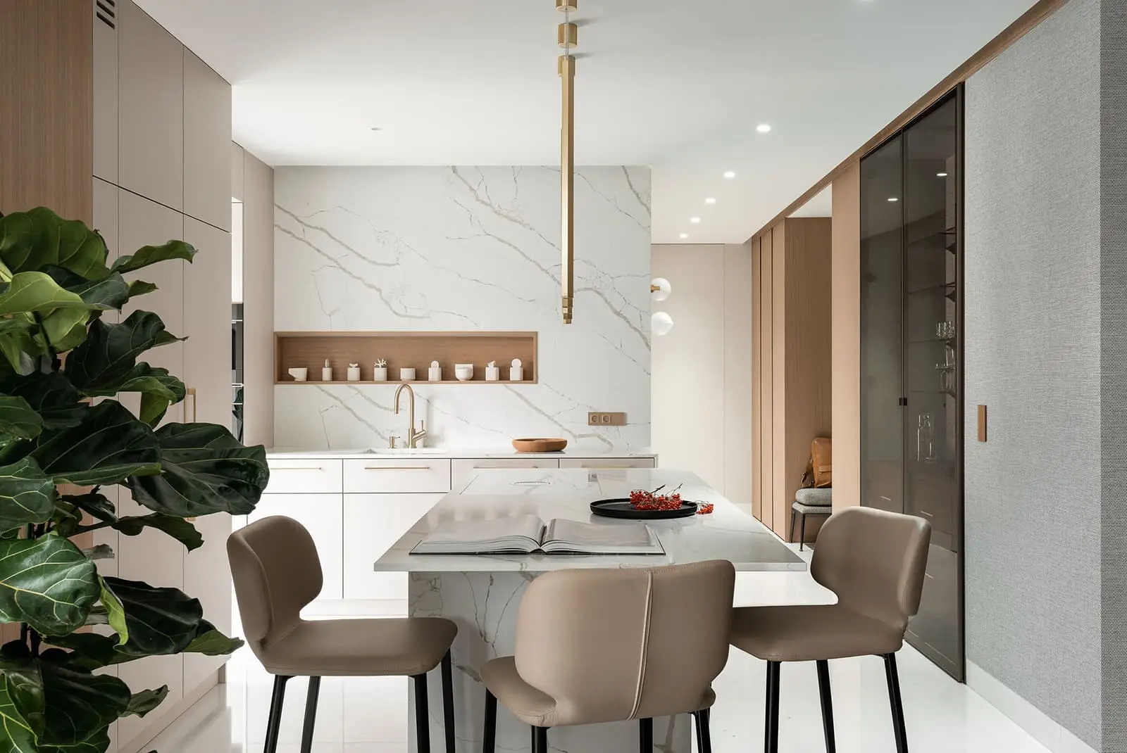 Elegancka wyspa kuchenna z białym marmurem, beżowymi krzesłami, złotą lampą wiszącą i zieloną rośliną w nowoczesnej kuchni w Gdańsku